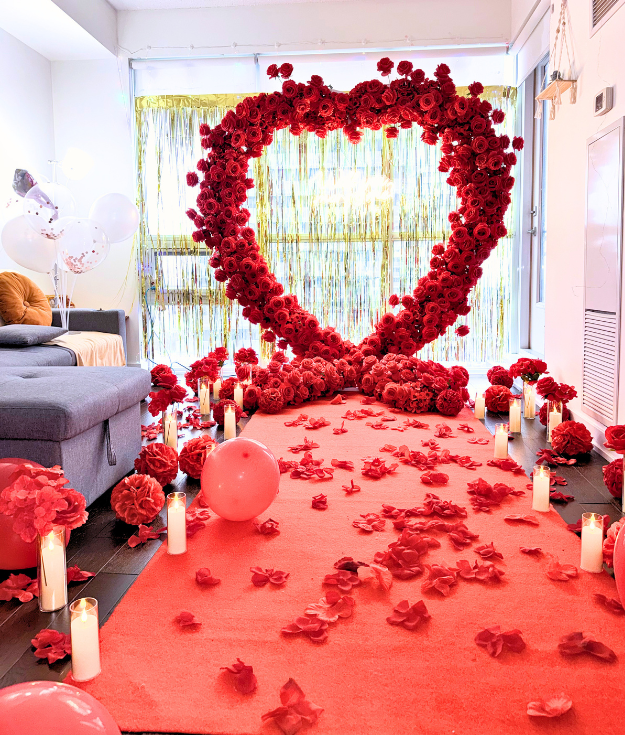 Luxury wedding proposal setup with rose backdrop, marquee letters, and candles