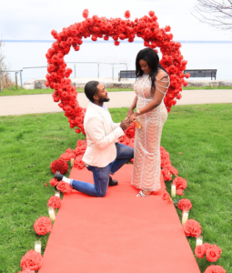 Romantic wedding proposal setup with flower wall, candles, and “Will You Marry Me” sign