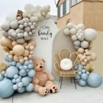 Balloon decor with two arches, garlands, teddy bear, and accent chair
