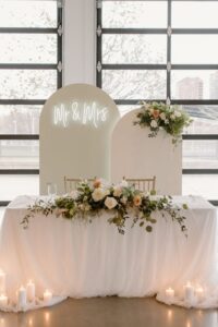 Elegant head table with lush floral arrangements and a romantic arch backdrop
