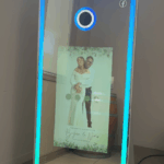 Lively party guests enjoying a mirror photo booth as confetti rains down around them, indicating celebration and excitement