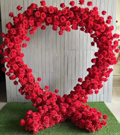 Heart-shaped red rose flower wall made with realistic silk flowers – romantic backdrop for weddings, proposals, and Valentine’s events